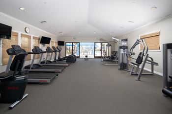 A gym with treadmills, elliptical machines, and other exercise equipment.